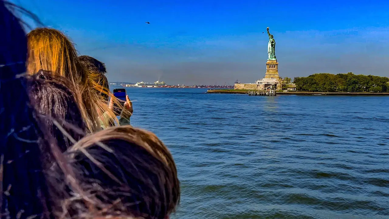 Turisti fotografano la Statua della Libertà dal battello