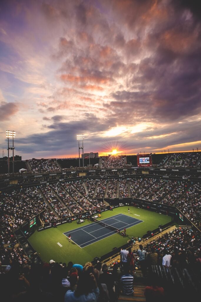 Uno stadio del tennis gremito al tramonto durante un torneo internazionale