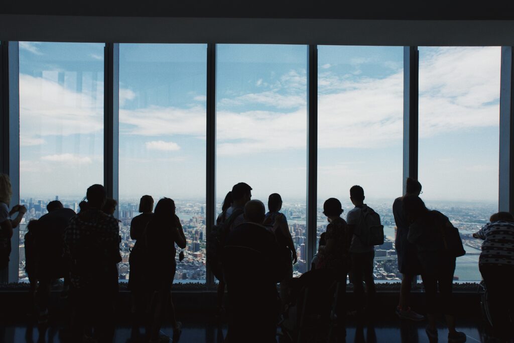 Visitatori in controluce davanti alle grandi vetrate di One World Observatory