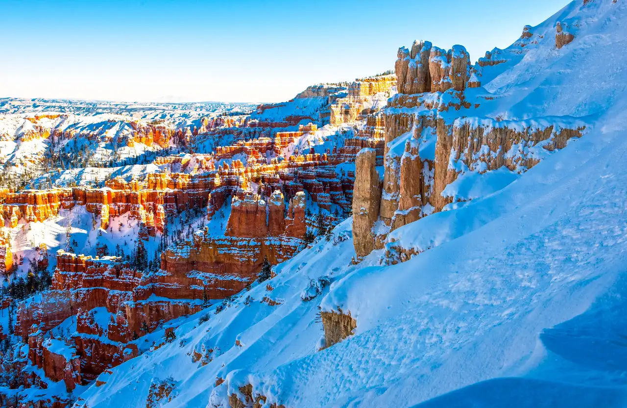 Gli hoodoos arancioni del Bryce Canyon ricoperti di neve sotto un cielo azzurro: l'anfiteatro del parco nazionale dello Utah in versione invernale.